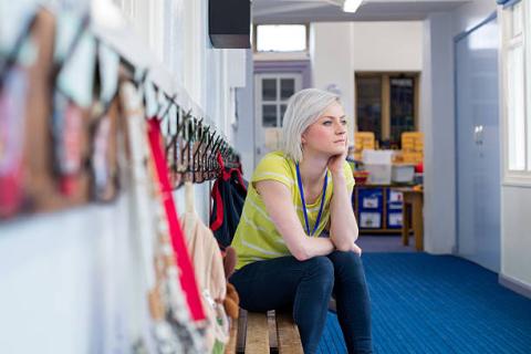 young teacher sitting at hooks staring thoughtfully