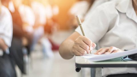 child writing with pen in class