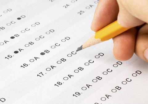 Student writing on multiple choice test paper
