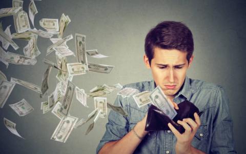 Man looking in wallet while money notes fly out of it